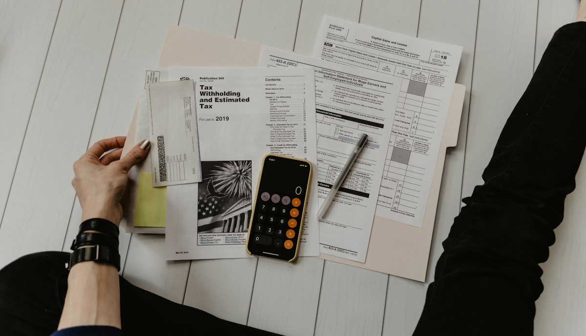 A hand using a calculator over financial paperwork